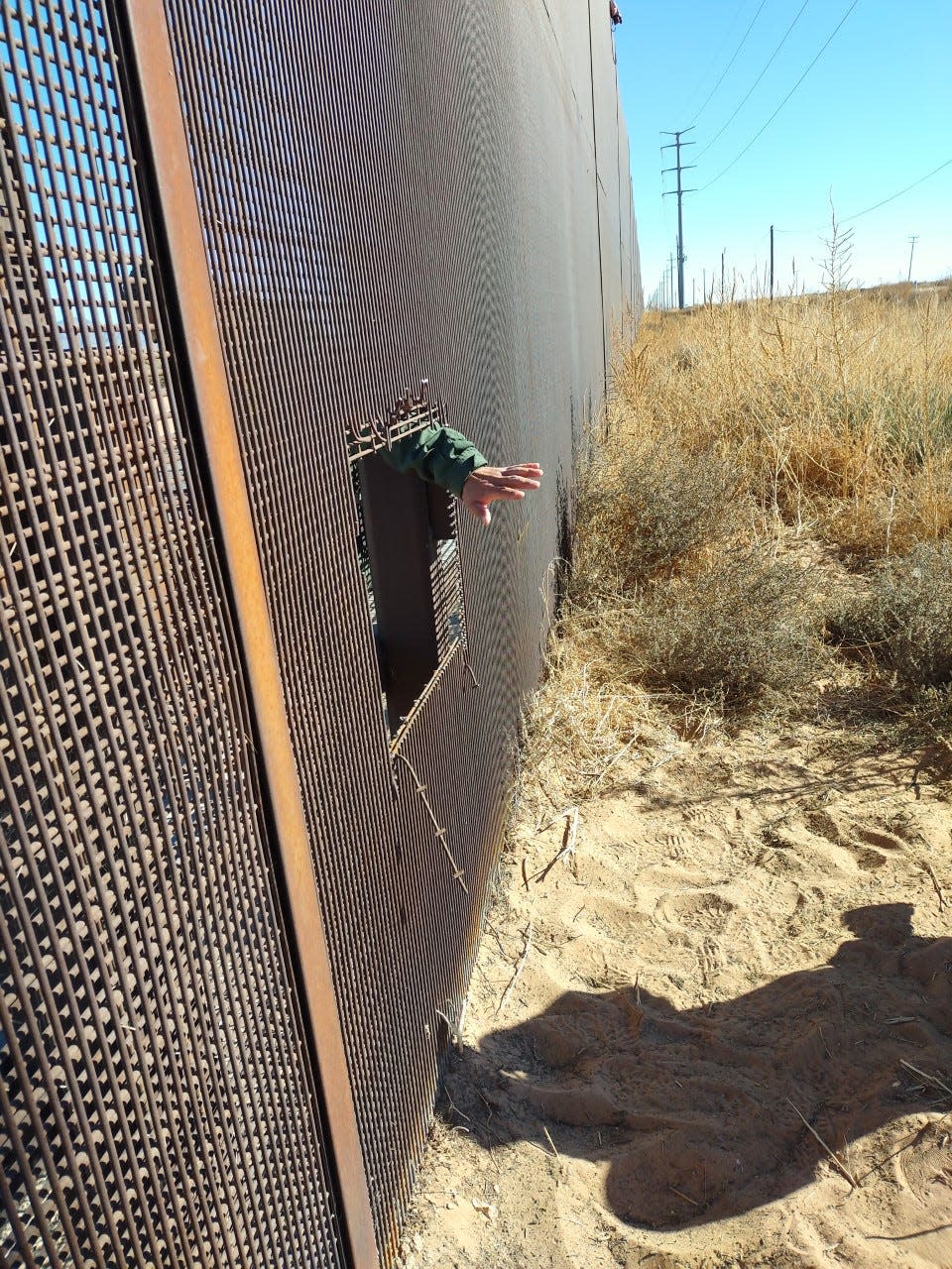 A United States border agent reaches a hand through a hole cut in the border wall separating the United States and Mexico on Dec. 29, 2021. The hole was likely cut to allow migrants to illegally enter the U.S. near Sunland Park, New Mexico, the agent said.
