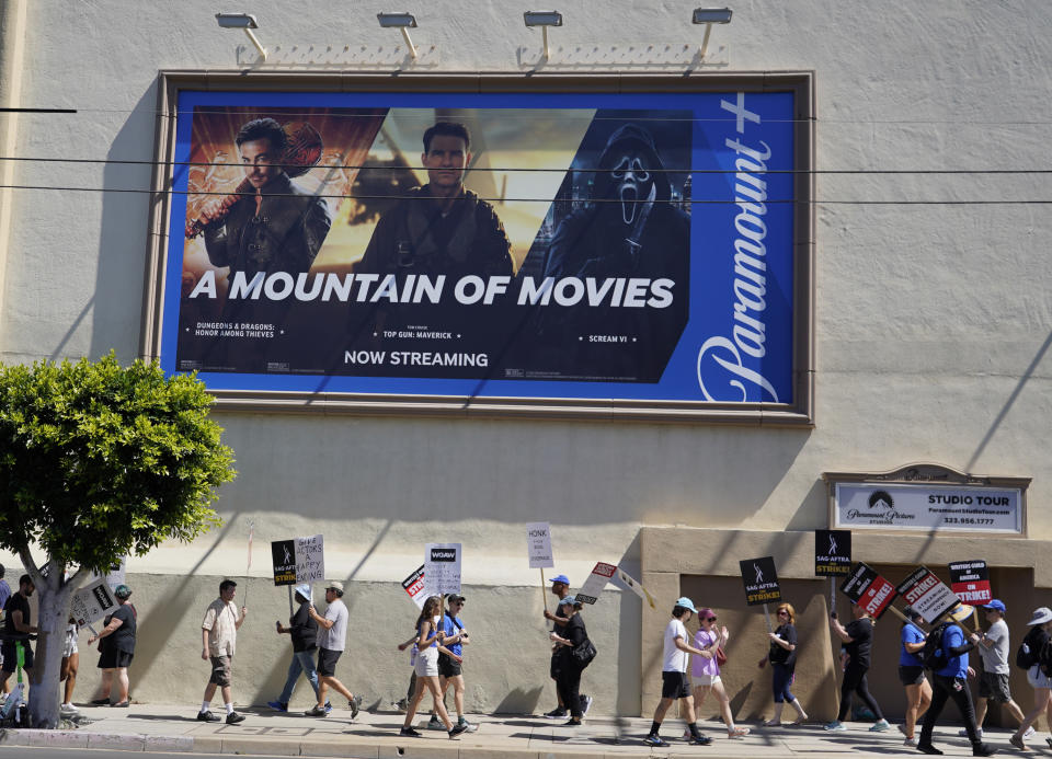 Un anuncio del servicio de transmisión Paramount+ aparece arriba de guionistas y actores en huelga en un mitin frente a los estudios Paramount en Los Angeles el viernes 14 de julio de 2023. (Foto AP/Chris Pizzello)