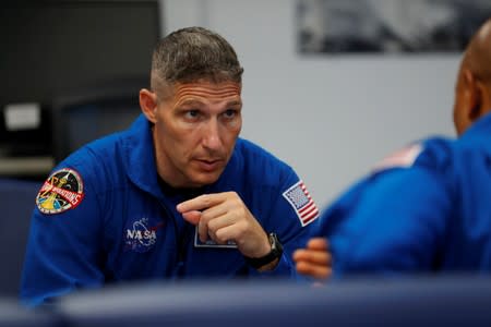 NASA commercial crew astronaut and Michael Hopkins talk over their flight procedures with fellow astronaut Victor Glover prior to a training flight in Houston, Texas