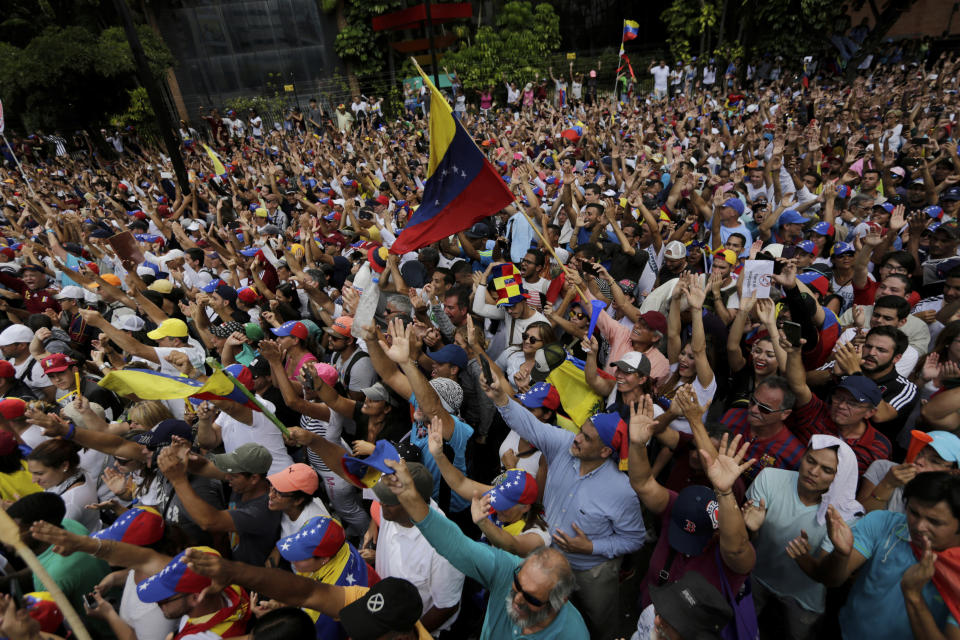 Anti-government protesters hold their hands up during the symbolic swearing-in of Juan Guaido, head of the opposition-run congress who declared himself interim president of Venezuela until elections can be called, during a rally demanding President Nicolas Maduro's resignation in Caracas, Venezuela, Wednesday, Jan. 23, 2019. Venezuela's crisis quickly escalated as the opposition leader backed by the Trump administration declared himself interim president in a direct challenge to Maduro, who retaliated by breaking off relations with the United States, his biggest trade partner. (AP Photo/Fernando Llano)