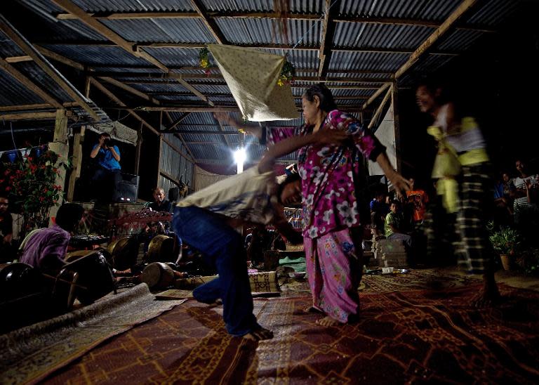 A Malaysian woman tussels with a shaman during her "main puteri" treatment at a village outside the city of Kota Bharu, June 8, 2014