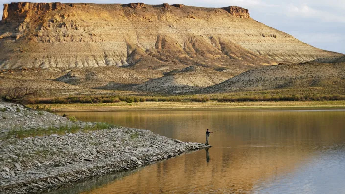 Nick Gann fishes in Firehole Canyon Friday, Aug. 5, 2022, on the far northeastern shore of Flaming Gorge Reservoir, in Wyoming. A boating and fishing paradise on the Utah-Wyoming line, Flaming Gorge is beginning to feel the effects of the two-decade megadrought gripping the southwestern U.S. (AP Photo/Rick Bowmer)