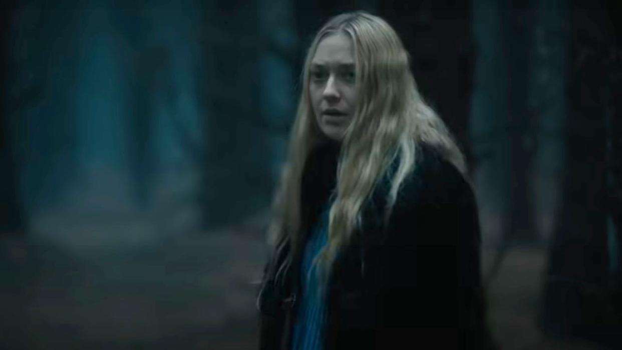  Mina (Dakota Fanning) looks over her shoulder as she walks through a forest in The Watchers. . 