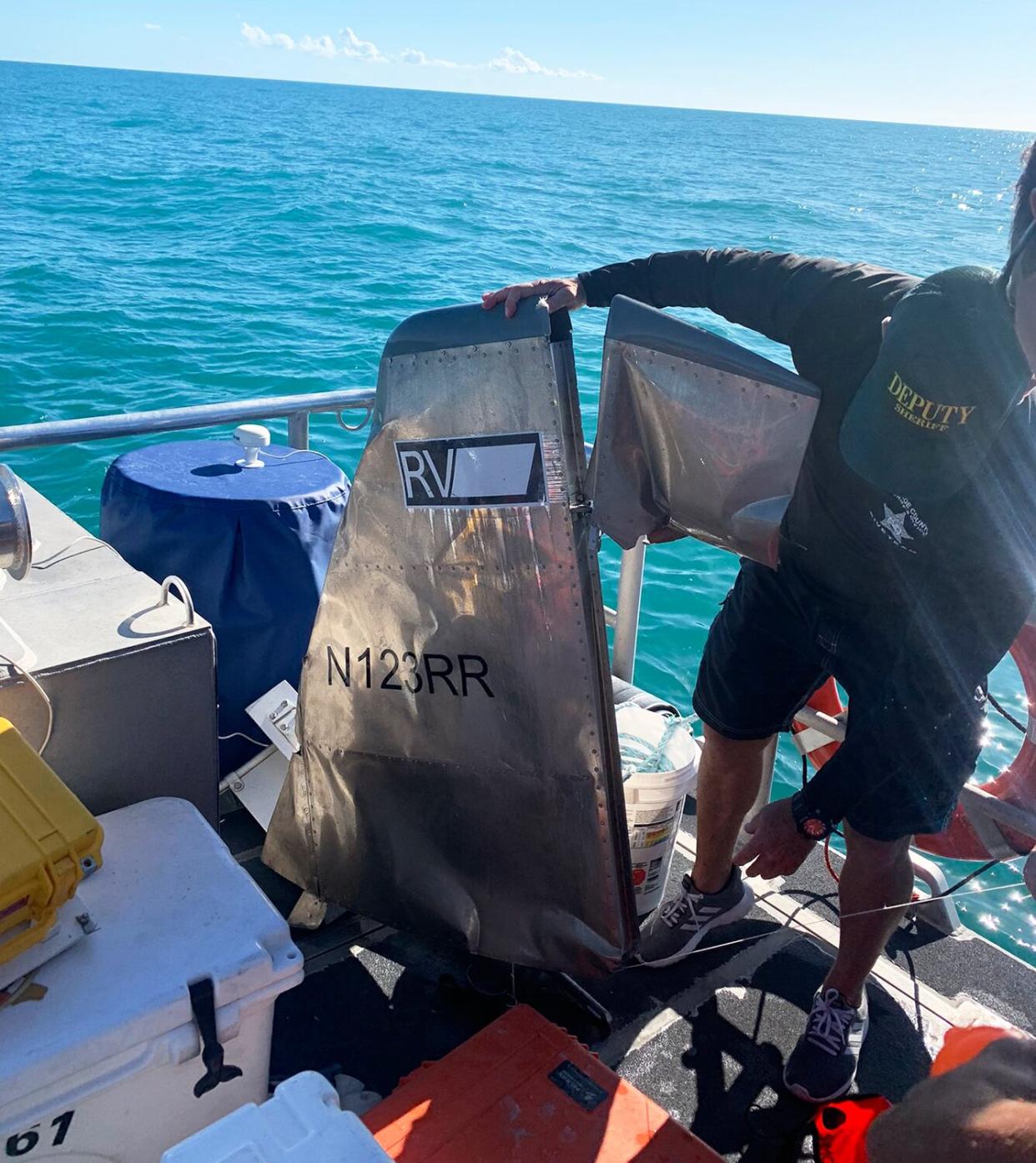 A Monroe County Sheriff's Office diver holds a piece of aircraft debris from the ocean floor 15 miles north of Big Pine Key, Florida, March 3, 2021. Coast Guard crews suspended the search March 3, 2021.