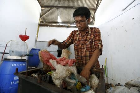 Hamidi places plastic waste into an iron box before burning and converting it to fuel at his workshop at TPA Rawa Kucing in Tangerang, Banten province, Indonesia March 17, 2016. REUTERS/Beawiharta