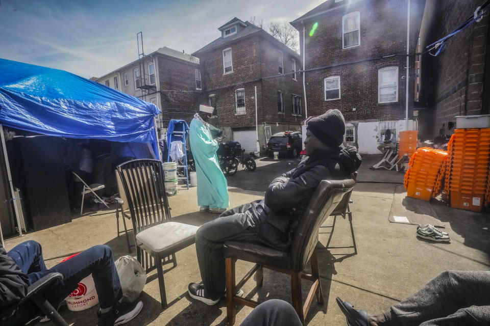 Senegalese migrant Malick Thiam, 29, center, listens during a conversation, as Imam Omar Niass, top, uses his phone while walking the backyard of Bronx's Masjid Ansaru-Deen mosque where migrants have installed tents, Friday, March 15, 2024, in New York. Imam Niass has repurposed the mosque, formerly his family home, as a refuge and shelter for hundreds of African migrants seeking asylum in the United States since 2020. (AP Photo/Bebeto Matthews)