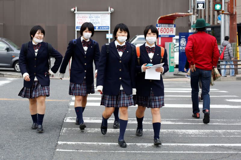 FILE PHOTO: Schoolgirls, wearing surgical masks, cross a street at lunchtime in Kyoto, western Japan