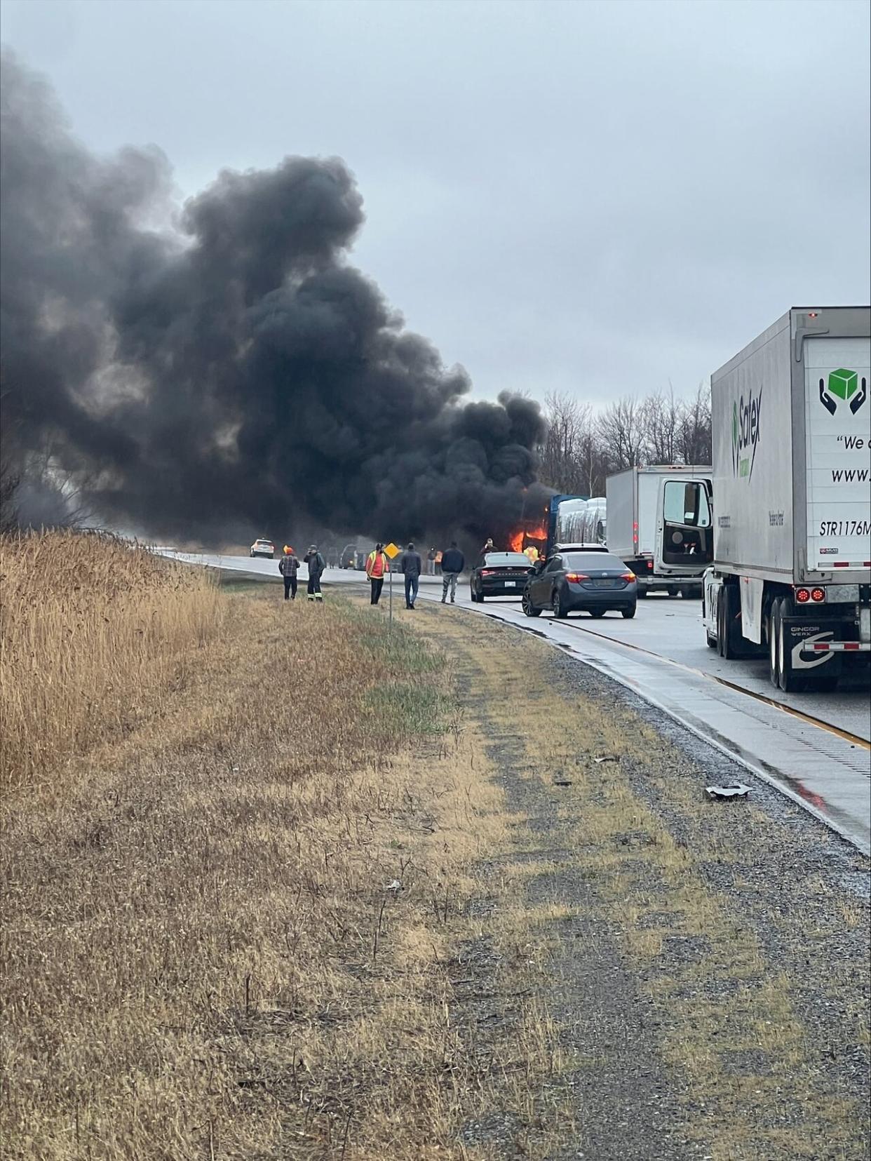 The westbound lanes of a section of Highway 417 near Limoges, Ont., reopened early Wednesday morning following a fatal crash Tuesday afternoon. Two people were pronounced dead at the scene, according to police. In this submitted photo, bystanders watch as a vehicle goes up in flames. (Submitted by Dave Dudley - image credit)