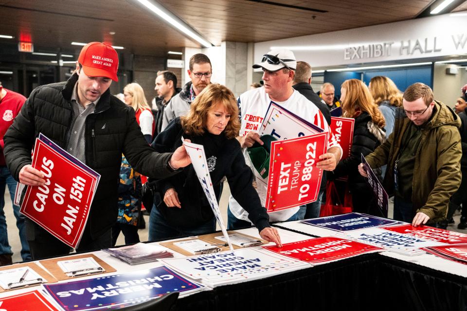 Supporters of former President Donald Trump grab signs at a campaign rally in Waterloo on Dec. 19, 2023. The Trump campaign has constructed a ground game in Iowa centered on dedicated "caucus captains" and turning out first-time caucusgoers.