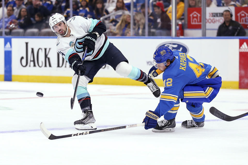 Seattle Kraken's Justin Schultz (4) passes the puck while under pressure from St. Louis Blues' Kasperi Kapanen (42) during the first period of an NHL hockey game Saturday, Oct. 14, 2023, in St. Louis. (AP Photo/Scott Kane)