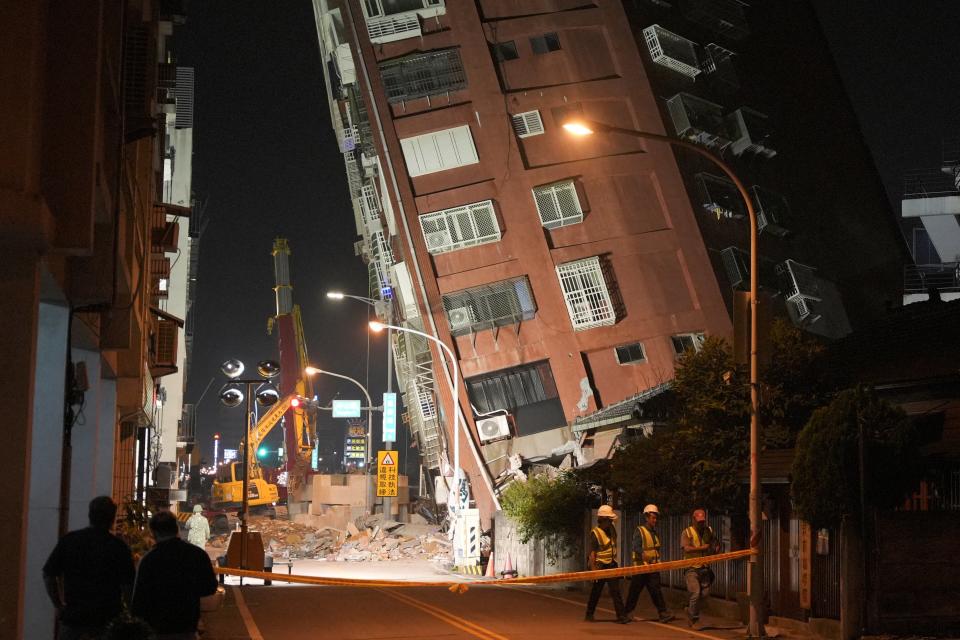 Workers walk at the site where a building collapsed, following an earthquake, in Hualien, Taiwan (REUTERS)