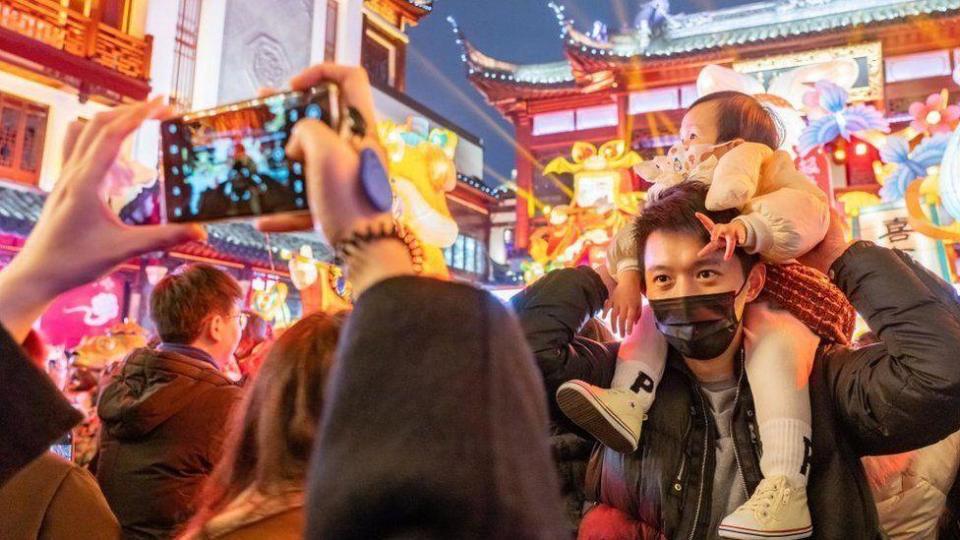 Un hombre posa para una foto con su bebé sobre sus hombros