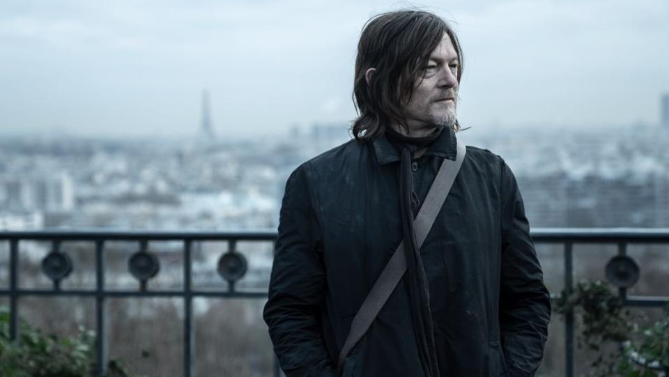 Daryl Dixon stands on a balcony with the Eifel Tower in the background on walking dead tv show 