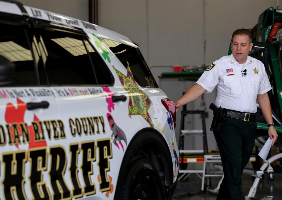 Sheriff Eric Flowers, along with sponsors and local representatives gather at the Indian River County Sheriff's Office hangar, Wednesday, July 26, 2023, to unveil their autism awareness vehicle.