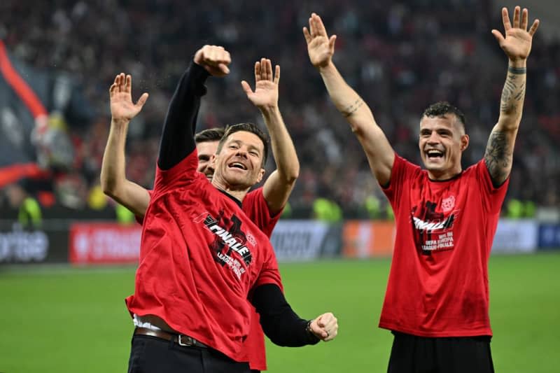 Leverkusen coach Xabi Alonso, Jonas Hofmann (l) and Granit Xhaka celebrate with the fans after wining the UEFA Europa League semi-final second leg match between Bayer Leverkusen and AS Roma in the BayArena. Federico Gambarini/dpa
