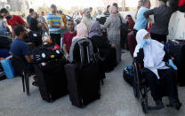 Passengers sit next to their luggage as they wait to cross the border to the Egyptian side of Rafah crossing, in Rafah, Gaza Strip, Tuesday, Aug. 11, 2020. Egypt reopened Rafah Crossing for three days starting Tuesday for humanitarian cases in and out of the Gaza Strip, including medical patients and people who had Egyptian and international citizenship. The border was closed since March. (AP Photo/Adel Hana)