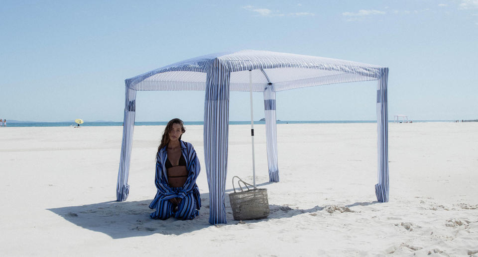 Model sitting in shade of CoolCabanas beach shelter