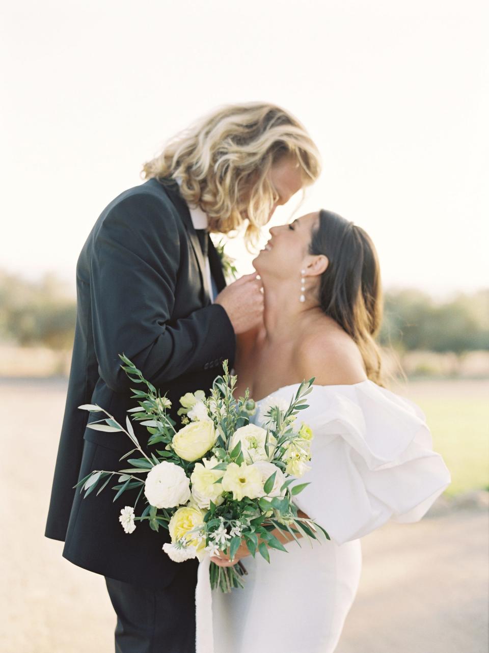 A bride and groom lean their heads together and smile in their wedding attire.