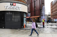 A woman wears a face mask as she walks past a closed shop, while a man cleans the pavement in Oxford Street, in London, Tuesday, Nov. 24, 2020. Haircuts, shopping trips and visits to the pub will be back on the agenda for millions of people when a four-week lockdown in England comes to an end next week, British Prime Minister Boris Johnson said Monday. (AP Photo/Alberto Pezzali)