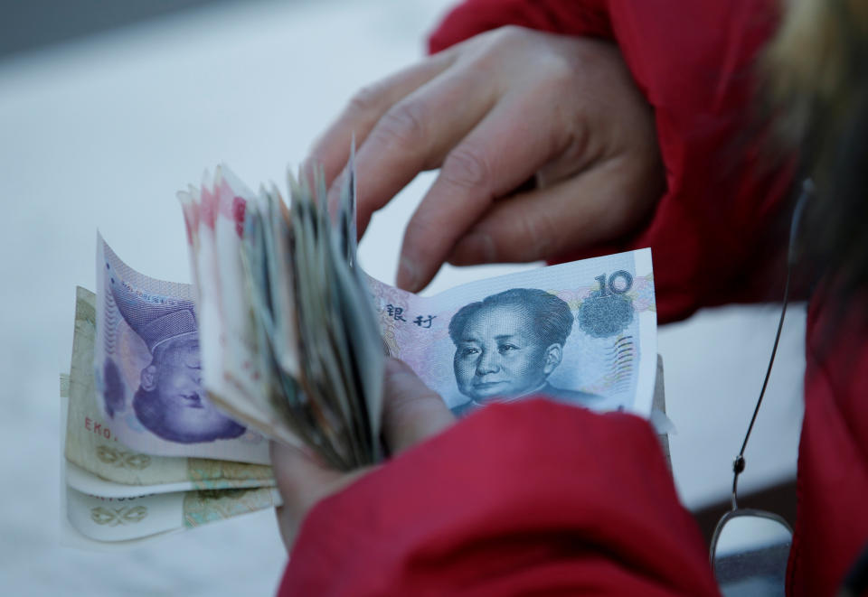 A woman counts Chinese Yuan banknotes as she sells tickets for a job fair in Beijing, China, February 11, 2017. REUTERS/Jason Lee