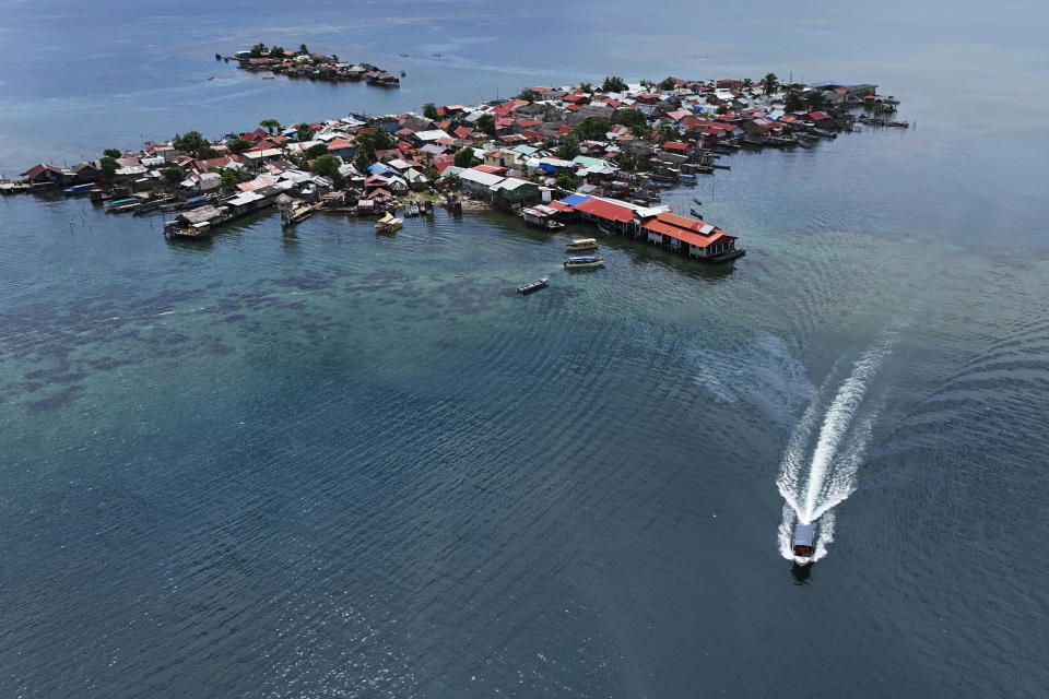 Funcionarios de protección civil trasladan las pertenencias de los residentes en un barco al continente desde la isla Gardi Sugdub, arriba, frente a la costa caribeña de Panamá, el miércoles 5 de junio de 2024. (AP Foto/Matías Delacroix)