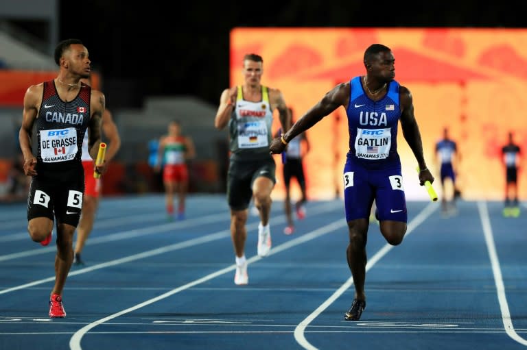 Andre De Grasse (L) of Canada and Justin Gatlin of the US cross the finish line during the IAAF/BTC World Relays Bahamas 2017, at Thomas Robinson Stadium in Nassau, on April 22