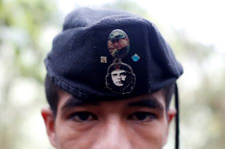 Eduar, a member of the 51st Front of the Revolutionary Armed Forces of Colombia (FARC), is seen wearing a cap with badges showing images of Che Guevara and FARC's late founder Manuel Marulanda at a camp in Cordillera Oriental, Colombia, August 16, 2016. REUTERS/John Vizcaino