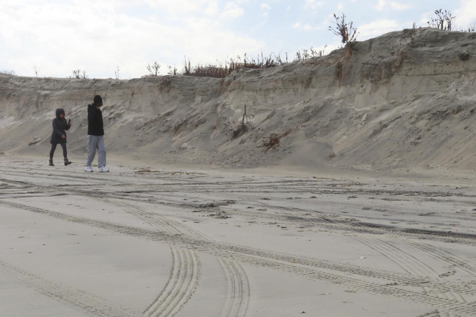 People walk along an eroded beach in North Wildwood, N.J., on Jan. 5, 2023. A judge on Feb. 1, 2023, denied the city permission to build a bulkhead to protect against erosion, but allowed it to move forward with a $21 million lawsuit seeking damages from the state to recoup the cost of sand the city trucked in at its own expense in the absence of a state and federal beach replenishment project. (AP Photo/Wayne Parry)