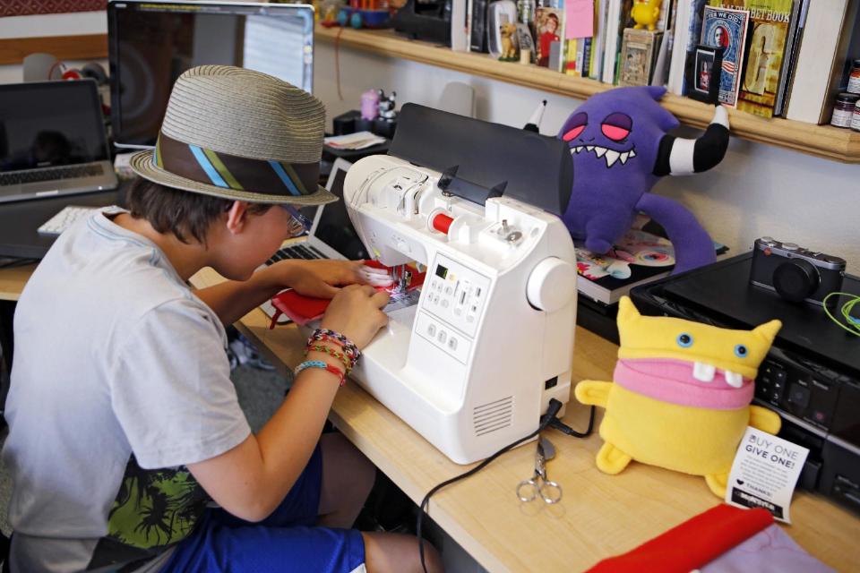 This photo taken on May 23, 2013 shows Ben Tollison sewing a monster doll at his home in Fort Collins, Colo. The Tollison family launched Monster to Love, a company that makes plush monster toys. (AP Photo/Ed Andrieski)