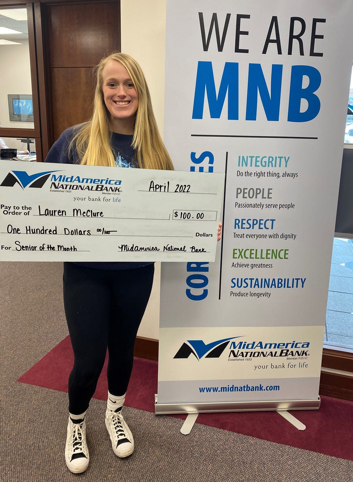 Lauren McClure holds an outsized check from MidAmerica National Bank.