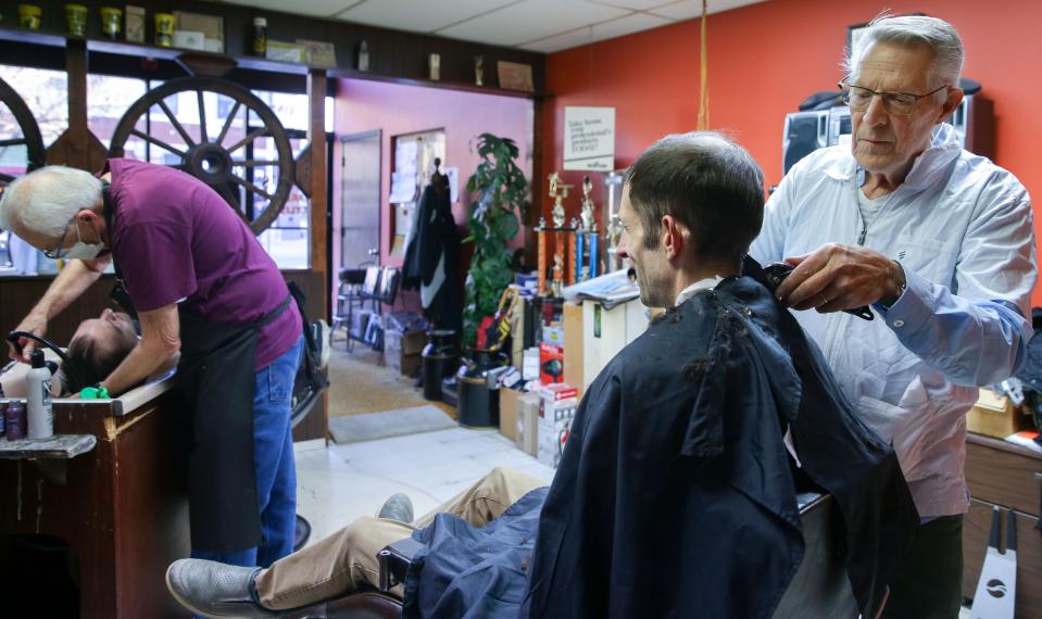 Tom Bergman, right, cuts Matthew Witry's hair as Stan Yoder, left, shampoos another client Wednesday, Dec. 13, 2023 in Iowa City, Iowa. The pair have worked together in Stan's barbershop on South Linn Street for about five decades.