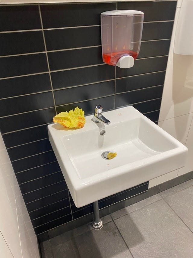 A cheeseburger wrapper left on the bathroom sink inside a McDonald's bathroom