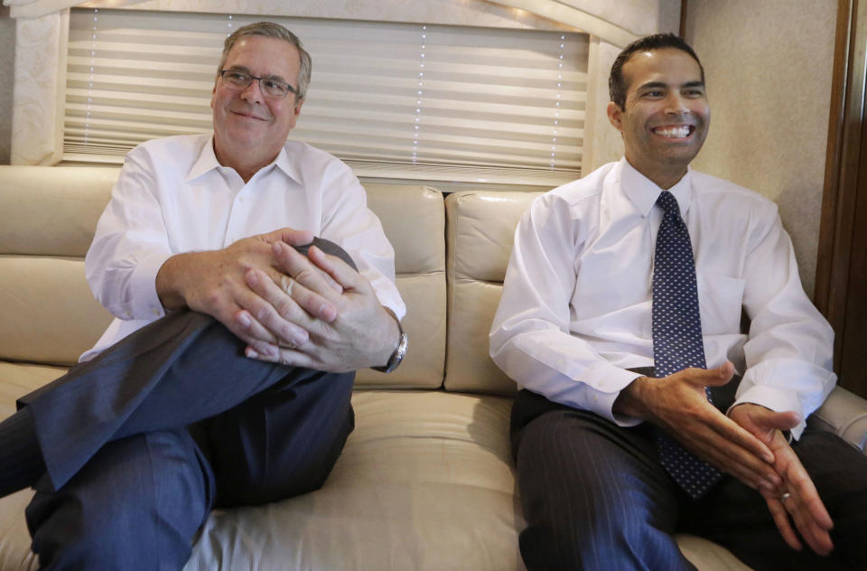 Former Florida Gov. Jeb Bush and his son, Texas Land Commissioner George P. Bush, sit on a campaign bus during an interview Tuesday, Oct. 14, 2014, in Abilene, Texas. (AP Photo/LM Otero)