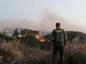 In this photo issued by the Guardia Civil, an officer looks at a forest fire in Gran Canaria, Spain, on Saturday Aug. 11, 2019. Spanish authorities say a wildfire on the Canary Island of Gran Canaria has burned 1,000 hectares (2,470 acres) and has forced the evacuation of 1,000 residents. (Guardia Civil Via AP)