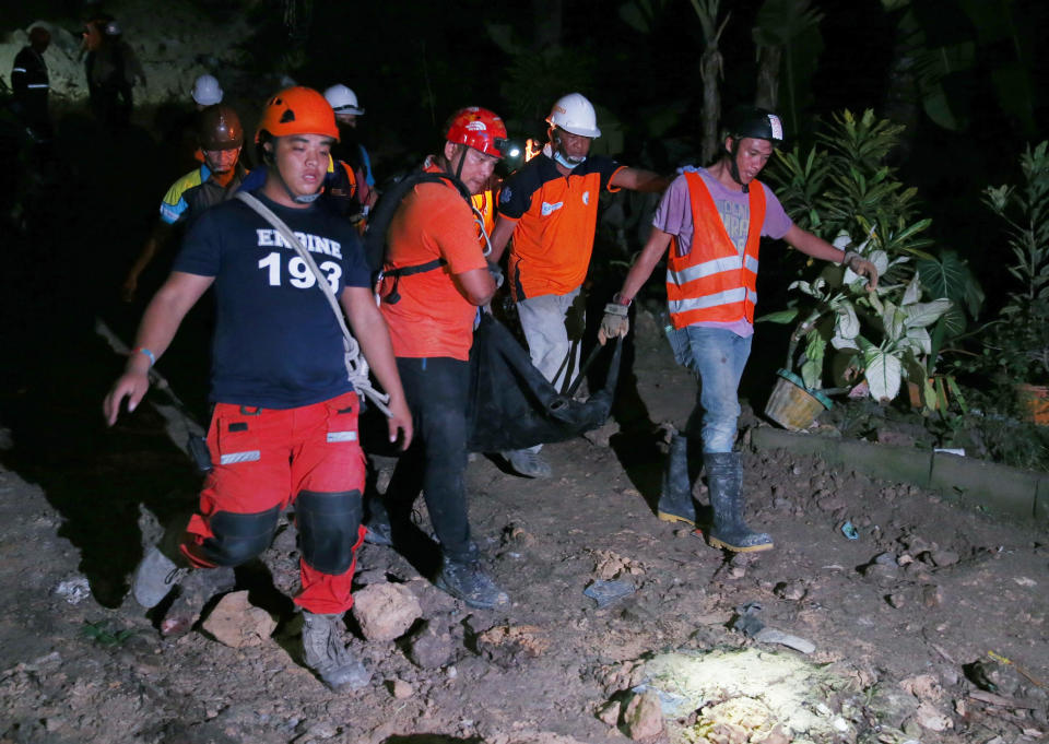 Rescuers carry a body of a child after being dug out of the rubble following a landslide that buried dozens of homes in Naga city, Cebu province central Philippines on Thursday Sept. 20, 2018. A landslide set off by heavy rains buried homes under part of a mountainside in the central Philippines on Thursday, and several people are feared buried, including two who sent text messages seeking help. (AP Photo/Bullit Marquez)