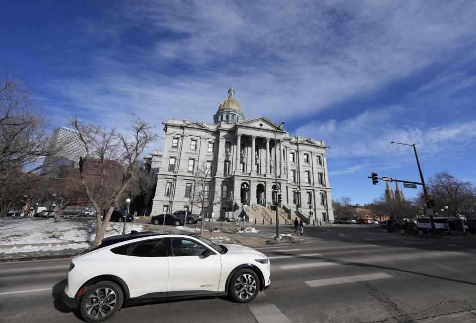 An 2022 Ford Mustang Mach E whips past the State Capitol as the legislative session opens in the House of Representatives in the Senate chambers Monday, Jan. 9, 2023, in Denver. Colorado is the second state in the union to have a majority of House and Senate seats filled by women and also has the largest LGBTQ caucus of any legislature in the country. (AP Photo/David Zalubowski)