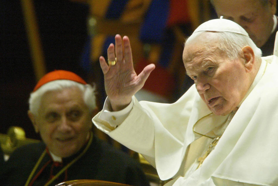 Pope John Paul II waves to cardinals and bishops at the Vatican in 2003 as then-cardinal Joseph Ratzinger looks on.