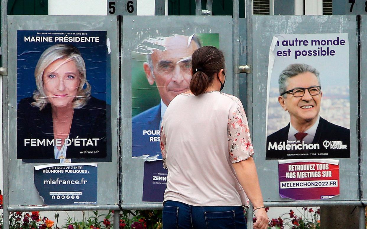 Man in 2022 looking at posters of Marine Le Pen and Jean-Luc Mélenchon