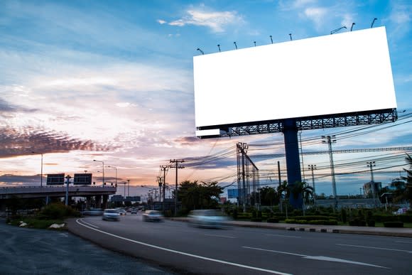 A billboard on the side of a busy highway.