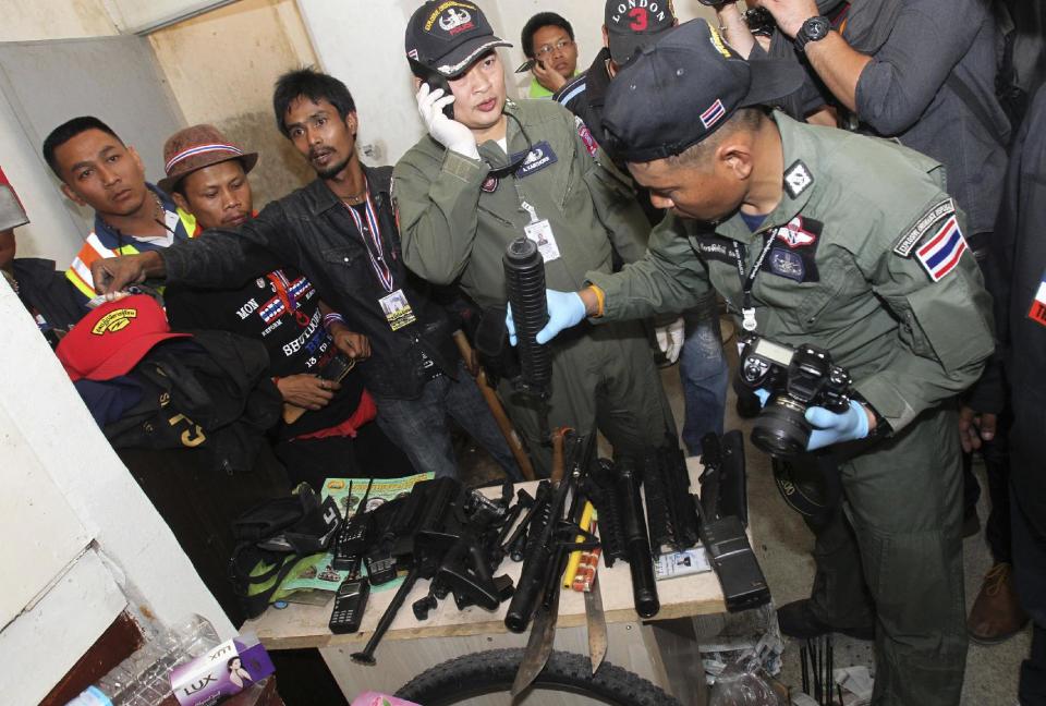 Thai police Explosive-ordnance-disposal members look at weapons they found at an abandoned building while searching for possible suspects near the scene of an explosion Friday, Jan. 17, 2014, in Bangkok, Thailand. Dozens of people were wounded in Thailand's capital Friday when a grenade was hurled at anti-government demonstrators marching through Bangkok at midday, an ominous development that raises tensions in the country's political crisis and the specter of more bloodshed to come. (AP Photo/Sakchai Lalit)