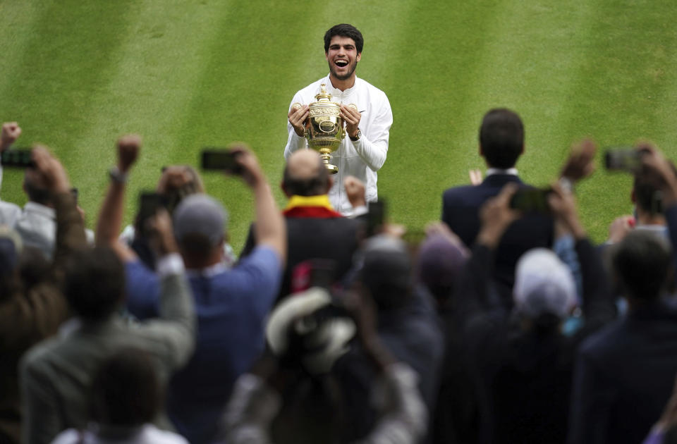 Spain's Carlos Alcaraz celebrates with the trophy after beating Serbia’s Novak Djokovic to win the final of the men’s singles on day fourteen of the Wimbledon tennis championships in London, Sunday, July 16, 2023. (John Walton/PA via AP)