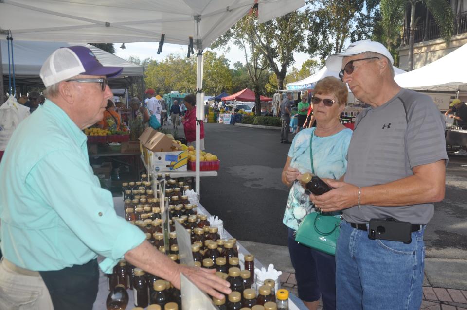 File: Don Murray talks to customers about the different types of honey and lets them taste samples. He mans a stand at the farmer’s market at the Promenade in Bonita Springs every Saturday during season.