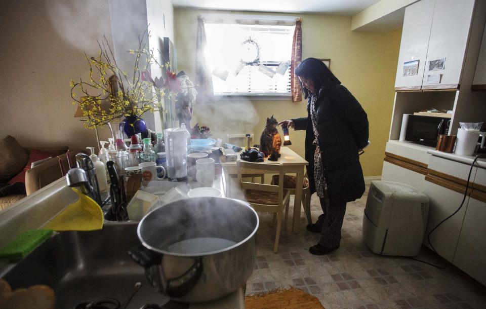 Crawley tends to her cat behind a pot of boiling hot water, used to raise the humidity in her home that has no heat or power following an ice storm in Toronto