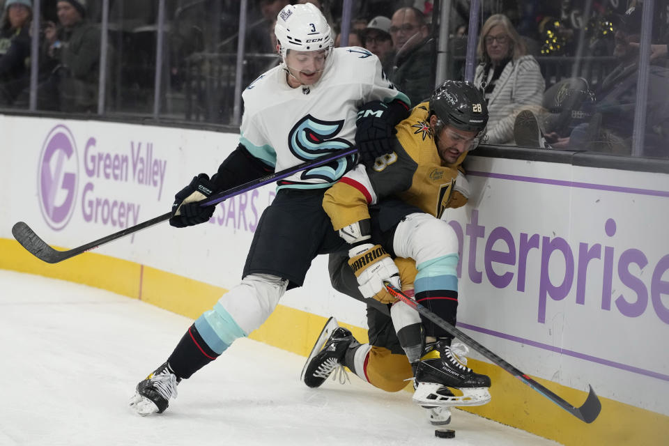 Seattle Kraken defenseman Will Borgen (3) and Vegas Golden Knights left wing William Carrier (28) battle for the puck during the second period of an NHL hockey game Friday, Nov. 25, 2022, in Las Vegas. (AP Photo/John Locher)