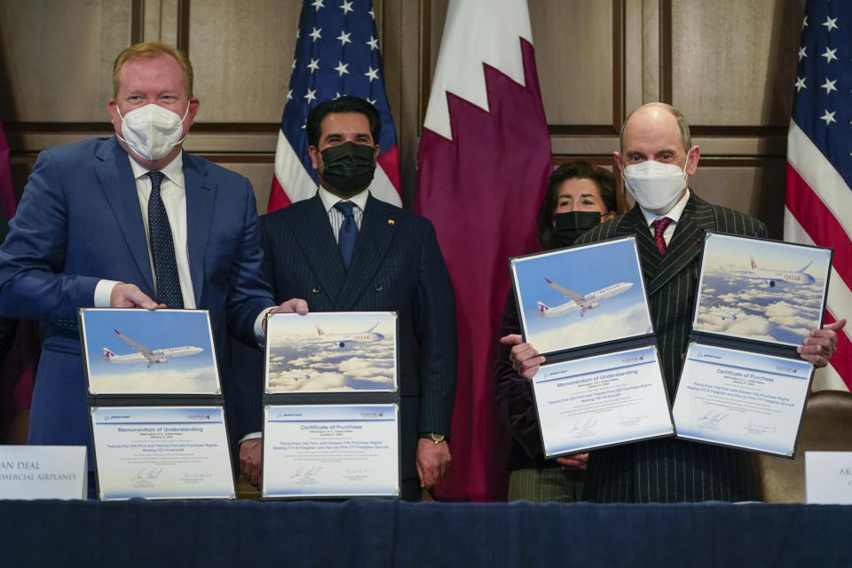 Stan Deal, President and CEO Boeing Commercial Airplanes, left, and Qatar Airways' CEO Akbar al-Baker, right, hold up signed agreements for the purchase of thirty-four 777-8 Freighter planes with purchase rights for an additional sixteen, in the Eisenhower Executive Office Building on the White House Campus in Washington, Monday, Jan. 31, 2022. Standing behind are Qatar's Emir Sheikh Tamim bin Hamad Al Thani, second from left, and and Secretary of Commerce Gina Raimondo, second from right. They also signed a letter of intent for an additional purchase from Qatar Airways of twenty-five 737-10s , worth $6.7 billion. (AP Photo/Carolyn Kaster)