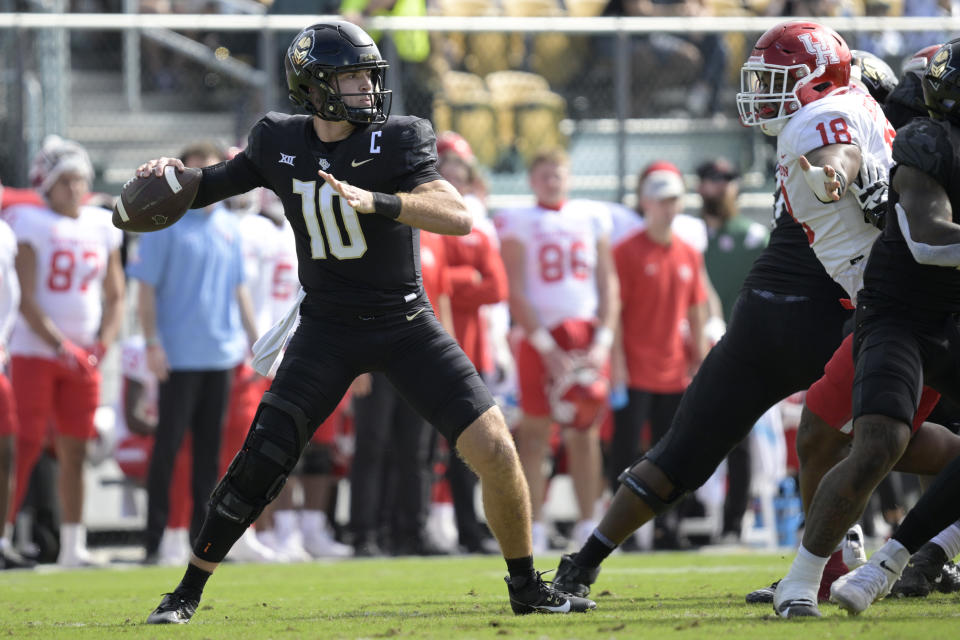 Central Florida quarterback John Rhys Plumlee (10) throws a pass in front of Houston defensive lineman Anthony Holmes Jr. (18) during the first half of an NCAA college football game, Saturday, Nov. 25, 2023, in Orlando, Fla. (AP Photo/Phelan M. Ebenhack)