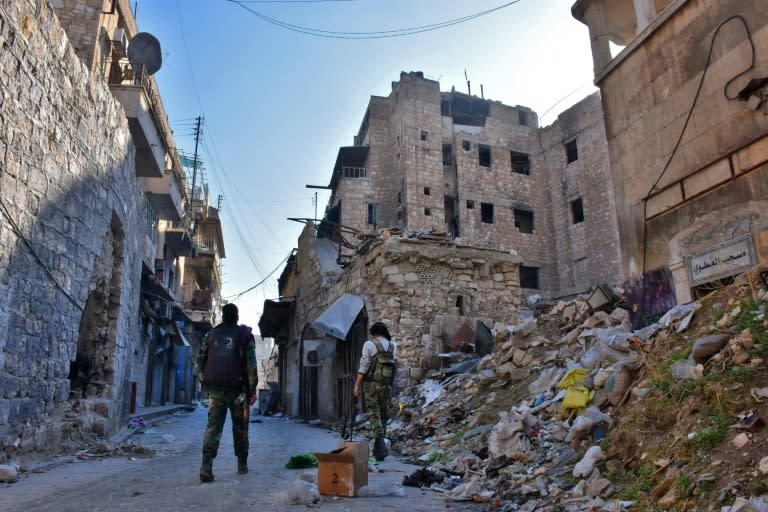 Syrian pro-government forces walk past rubble in old Aleppo on December 9, 2016