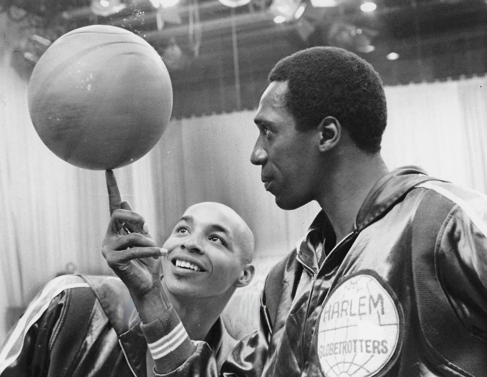 Curly Neal admires Meadowlark Lemon's ball-spinning technique with the Harlem Globetrotters in 1968.