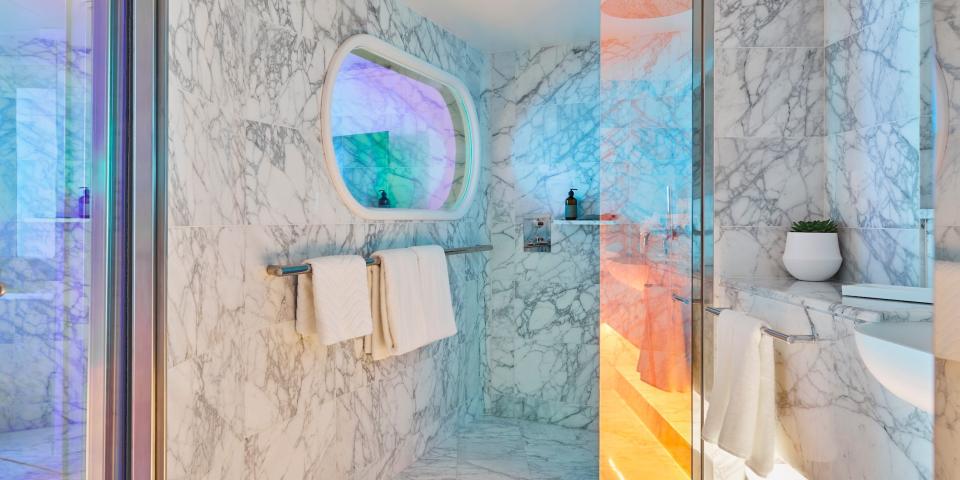 a marble shower with rainbow reflective glass doors