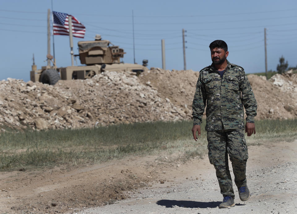 FILE - In this April 4, 2018 file photo, a U.S-backed Syrian Manbij Military Council soldier passes a U.S. position near the tense front line with Turkish-backed fighters, in Manbij, north Syria. Some hundreds of U.S. troops are stationed in Syria, raising the possibility of an unintended confrontation between two NATO members playing out if Turkey launches an operation in the area. (AP Photo/Hussein Malla, File)